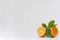 Citrus with half juicy oranges and green leaves on white wood table.