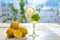 Citrus iced lemonade in pitcher and lemons glasses with lemon slice decoration and on marble table on natural background