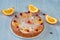 Citrus pie with caramelized oranges and powdered fresh red berries on the gray surface. Just backed pie with raw orange slices