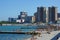 City beach and breakwaters against the backdrop of modern apartment buildings. People bathe and sunbathe.