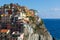 City built on a cliff overlooking the sea. Manarola in the Cinque Terre area in Italy. Colorful residential buildings on the blue
