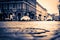 City central square after rain, car traveling on the street and pedestrians cross the road.