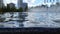 City fountain. Water flows and shines in the sun. Blurred background