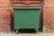 City green garbage container rubbish bin dustbins outside against brick wall background with copy space