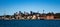 City Harbourside houses, wharf and boat sheds on Sydney Harbour with city CBD skyline in background against blue sky