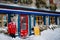 City after heavy snowfall, colorful shops doors