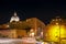 City life in central Rome and view of the Basilica di San Pietro dome. Night scene