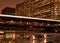 City night lights are illuminated from Chicago bridge and moving el train speeding across it.