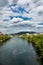 The city of Ourense in Galicia, Spain. View of the Minho river from the Roman Bridge under beautiful cloudy blue sky on a spring