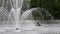 City park fountain jet in the lake with people fishing on the boat