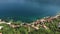 City sandy beach with a pier and coastal dwelling houses in the town of Petrovac. Aerial view
