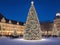 City square with a giant illuminated and decorated christmas tree with people around it