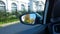 City street through the car side rear view mirror. Cityscape through vehicle window. Travelling by automobile. Orange and yellow t