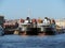 City view with houses, bridge, harbour and two black ships moored in port