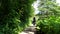 City woman with backpack walking gravel footpath through bushes