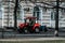 City worker in red tractor clears street in early morning. Small tractor cleans city sidewalks from dust and dirt. street cleaning