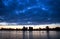 Cityscape buildings under construction on background of lake and girl with paddle on water board and sunset dramatic sky