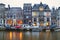 Cityscape - evening view of the houses with festive decorations and the city channel with boats, city of Amsterdam