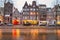 Cityscape - evening view of the houses with festive decorations and the city channel with boats, city of Amsterdam
