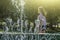 Cityscape with gush water of fountain. Silhouette of young woman walking behind splashes of fountain on hot summer day