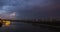 Cityscape with river traffic and movement of the clouds at dusk