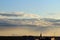 Cityscape, rooftops and antennas against the skyline and sky at dusk. Golden cross on the spire of a Babtist church at