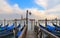 Cityscape with venice blue gondolas on st. mark`s square docks and cloudly sunset on St. Giorgio island with warm colors in backgr