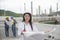 Civil Engineer holding portable radio, blueprint at refinery plant. Asian woman engineering fill out form and inspect at