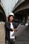 Civil engineer man with helmet, standing and looks at the project drafts while on parallel expressway background