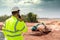 A civil engineer is using a construction telephone on the construction site in the background with loaders and dumpers