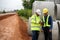 Civil engineers discuss the job with construction foreman while using technology tablet at highway road