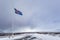 A civil flag and ensign Iceland against a clouded sky.
