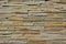 Cladding of tiles which have the shape of elongated strips resembling stone. the color changes from yellowish brown to green.