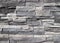 Cladding wall made of  stacked  rough natural stones. Colors are shades of gray