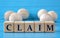CLAIM - word on wooden cubes on a blue background with wooden round balls