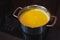 Clarification of butter, clarified butter in a steel pot mixed with steel spoon. Removing foam from butter