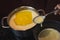 Clarification of butter, clarified butter in a steel pot mixed with steel spoon. Removing foam from butter