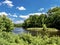 Clarion River in Cooks Forest State Park in Pennsylvania with green trees and a bright blue sky filled with white clouds.