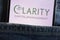 Clarity Capital Management logo displayed on smartphone hidden in jeans pocket