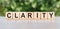 CLARITY word written on wooden blocks. The text is written in black letters and is reflected in the mirror surface of the table.