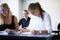 In class with friends. A smiling teenage girl sitting in a classroom with other students.