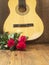 Classic acoustic guitar on a wooden floor and bouquet of red rosses. Expression of gratitude and love for great music performance