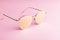 Classic aviator mirrored flat lens sunglasses with golden metal frame closeup on pink background