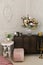 Classic bedroom interior. A brown wooden chest of drawers, flowers in a glass vase, and a white bedside table