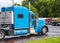 Classic blue big rig powerful semi truck tractor moving on the exit of truck stop to street