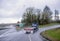 Classic blue big rig semi truck with empty flat bed semi trailer running on the highway exit going uphill in raining weather with