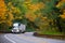 Classic bonneted semi truck ribbed trailer on road autumn forest