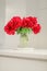 Classic bouquet of red peonies in a glass vase indoors, home decor