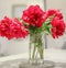 Classic bouquet of red peonies in a glass vase indoors, home decor