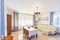 Classic bright living room with wooden furniture in the house. In the center is a table with fruit and four wicker chairs.